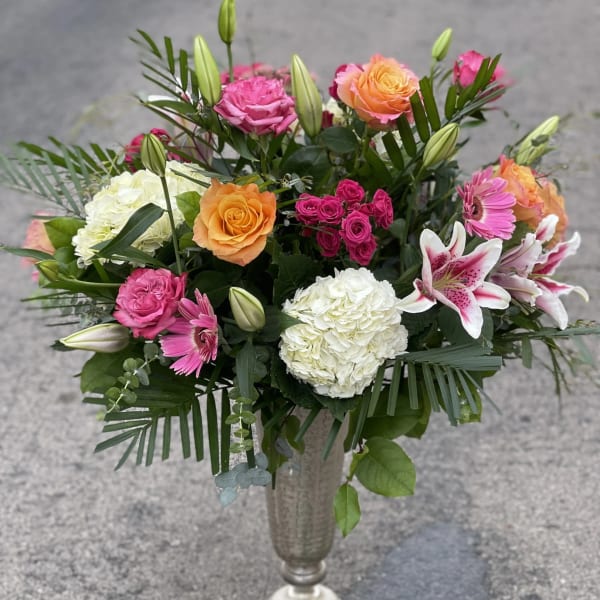Mixed bouquet of pink and orange roses with lilies in a tall vase