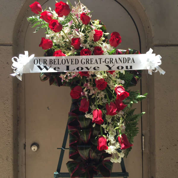 Standing sympathy spray of red roses with a memorial ribbon