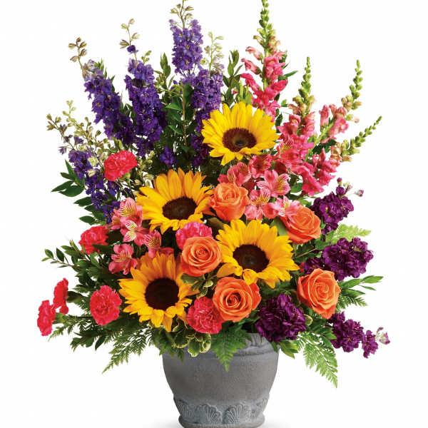 Mixed bouquet with sunflowers, roses, and purple spikes in a gray vase