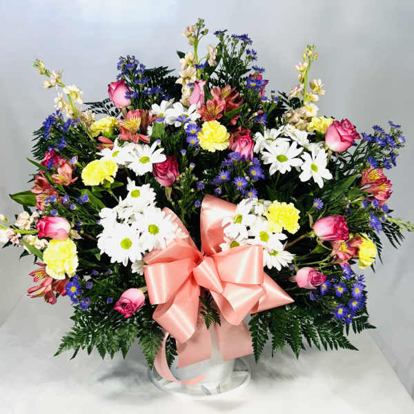 Mixed bouquet of daisies, roses, and carnations with a pink ribbon