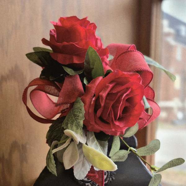 Red roses arranged on a memorial lantern with a framed tribute panel