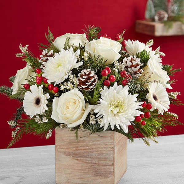 White roses and daisies in a wooden box with pinecones and red berries