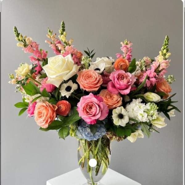 Mixed pink and peach flowers arranged in a clear glass vase