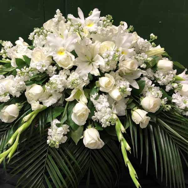 White floral casket spray with lilies, roses, and orchids