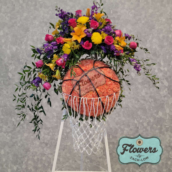Basketball-shaped floral arrangement on a stand with pink, yellow, and purple flowers