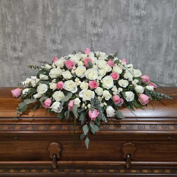 White and pink rose casket spray on a wooden casket