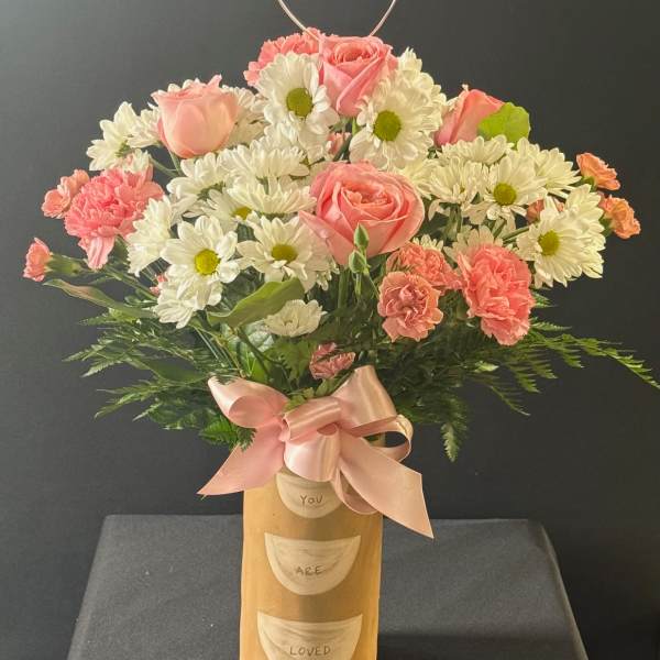 Pink roses and white daisies in a gold vase with a heart topper