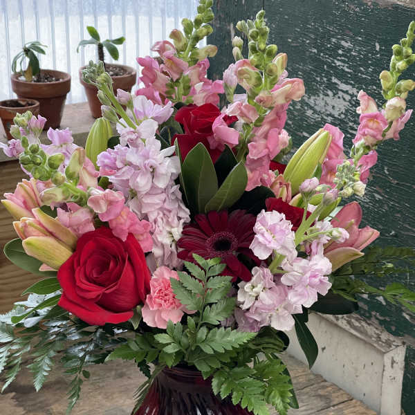Mixed pink and red flower arrangement in a burgundy vase