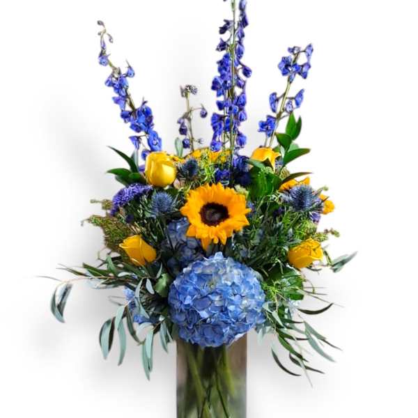 Blue and yellow mixed flower arrangement in a glass vase