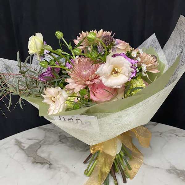 Pastel bouquet with pink and white blooms wrapped in pale paper