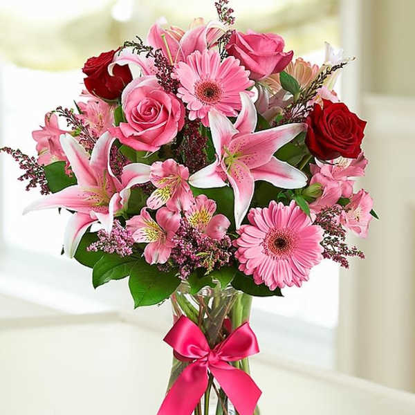 Pink and red mixed bouquet in a glass vase with a ribbon