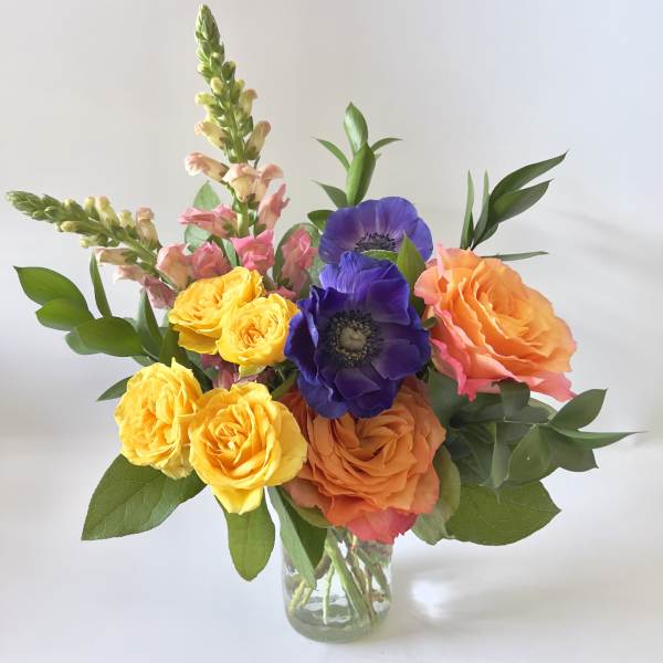 Colorful bouquet of roses and purple anemones in a glass vase