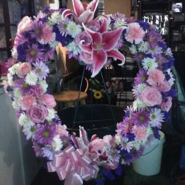 Heart-shaped floral wreath with pink lilies, roses, and purple daisies
