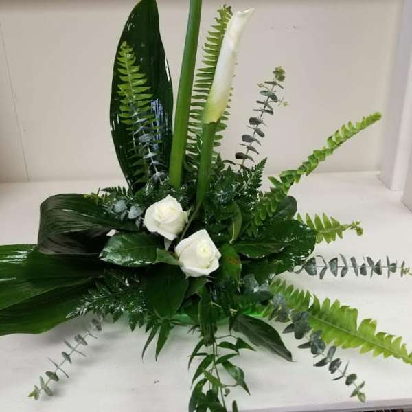 White calla lilies and roses in a low green arrangement