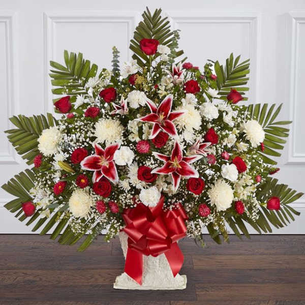 Large red and white floral spray with lilies and roses in a white vase