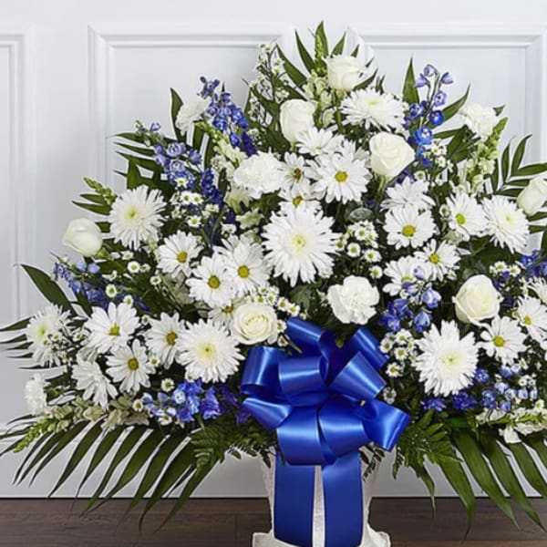 White floral standing spray with blue ribbon and daisies