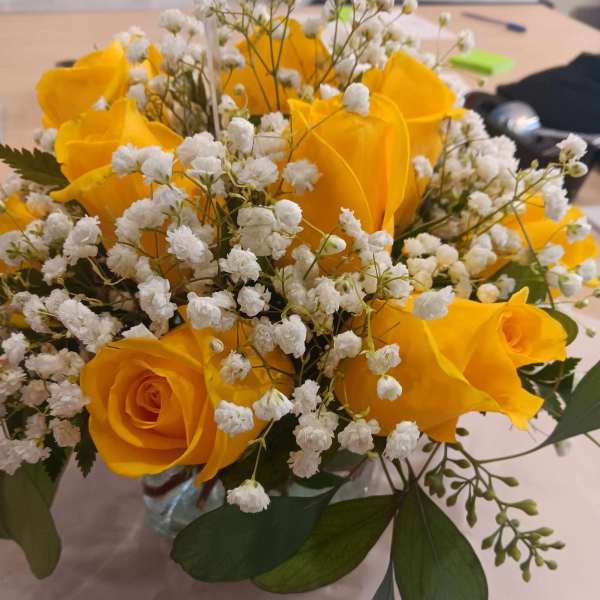 Yellow roses with white baby's breath in a glass vase