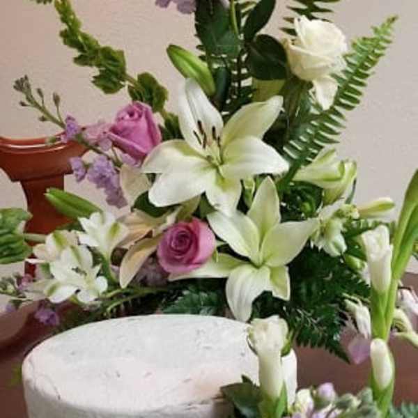 Pink roses and white lilies arranged with purple filler flowers
