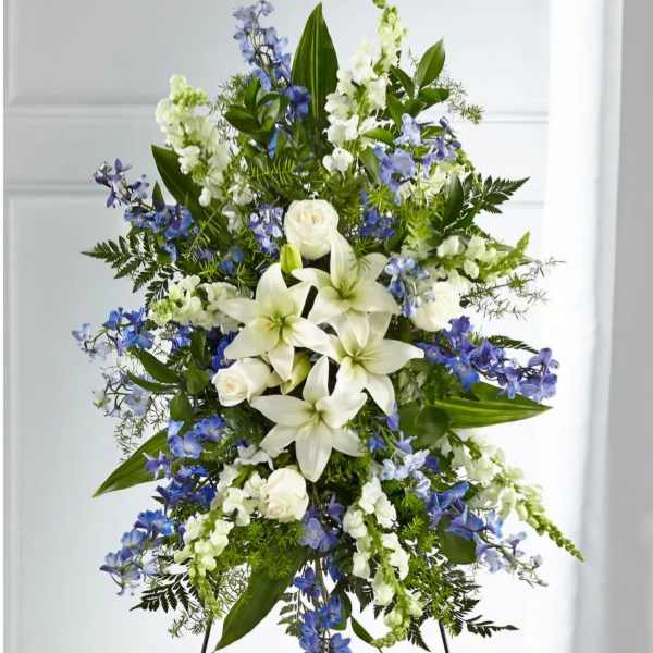 Standing floral spray with white lilies, white roses, and blue flowers