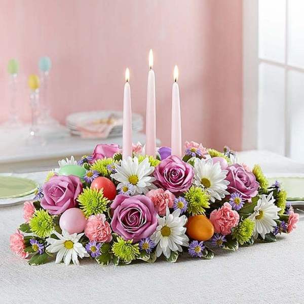 Floral centerpiece with pink roses and white daisies around three candles