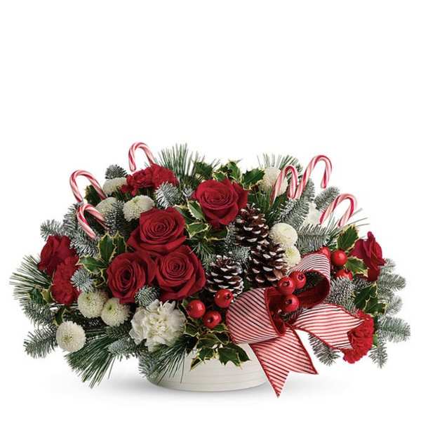 Christmas arrangement with red roses, pinecones, and candy canes in a white bowl