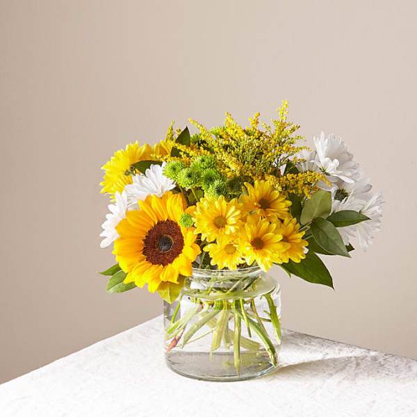Yellow and white flowers arranged in a clear glass vase