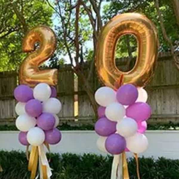 Two gold number balloons with purple and white balloon clusters