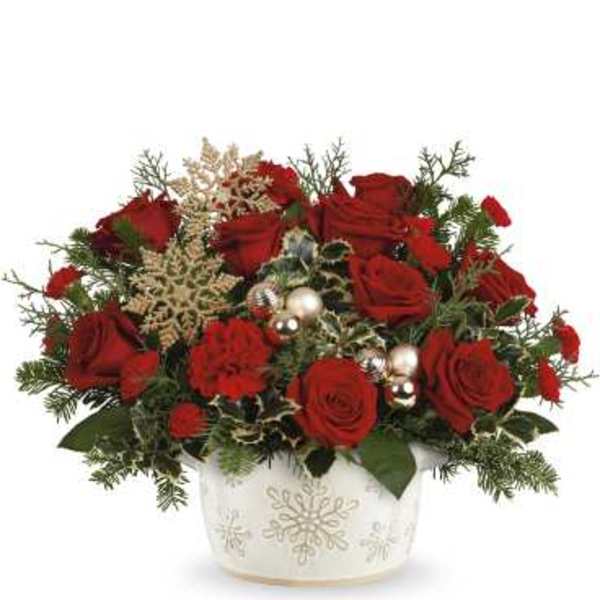 Red roses in a white snowflake vase with holiday accents