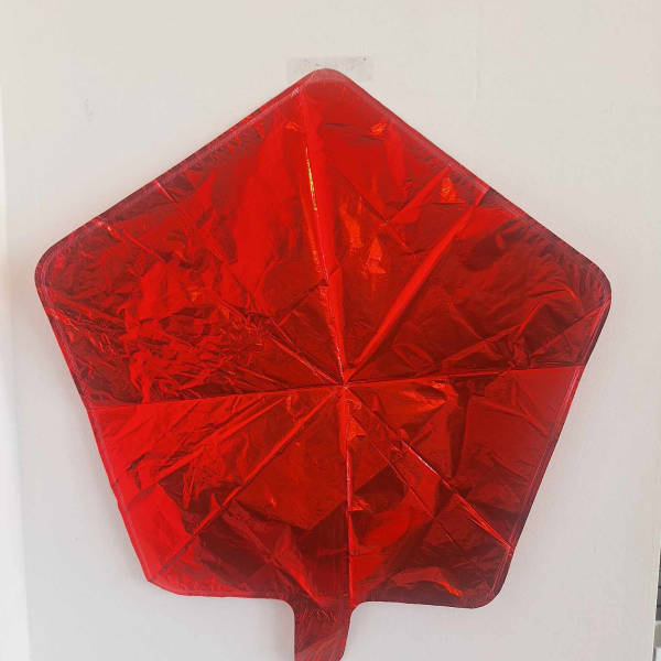 Red star-shaped foil balloon on a white wall