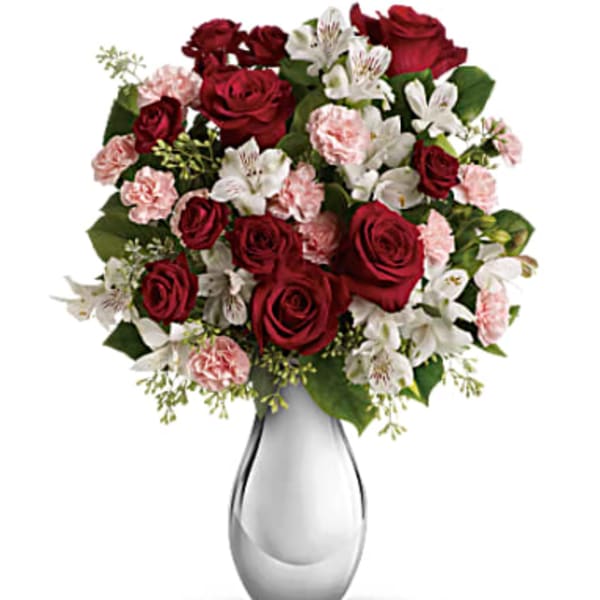 Red roses and pink carnations in a clear glass vase