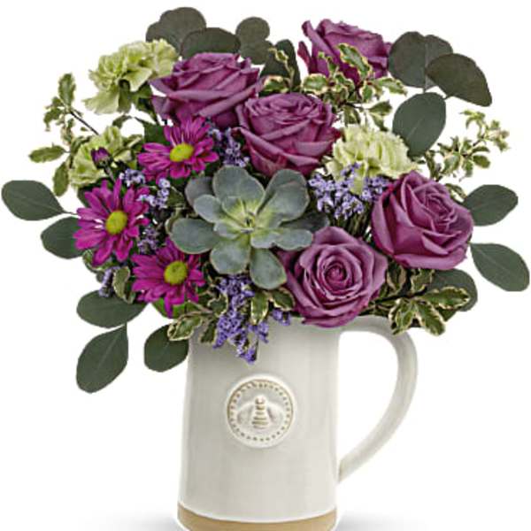 Purple roses and daisies arranged in a white ceramic mug