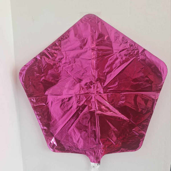 Pink metallic star-shaped balloon against a plain wall
