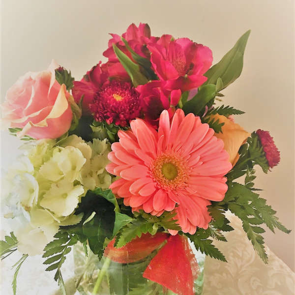 Mixed bouquet in a clear glass vase with pink gerbera daisies and roses