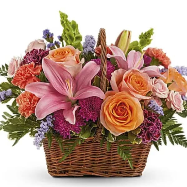 Basket of pink lilies and peach roses with purple filler flowers