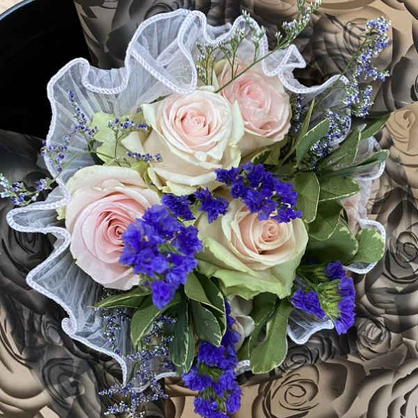 Bouquet of pale pink roses with purple filler flowers and white mesh wrap