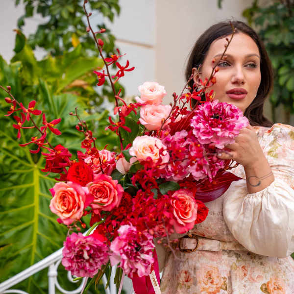 Woman holding a large bouquet of pink and red flowers