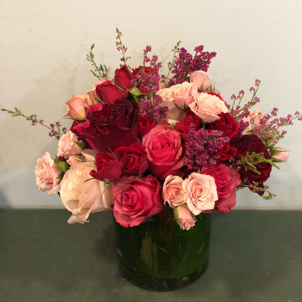 Red and pink roses arranged in a dark glass vase
