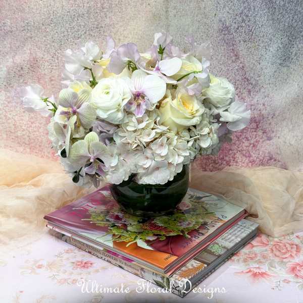 White and pale lavender floral arrangement in a dark glass vase