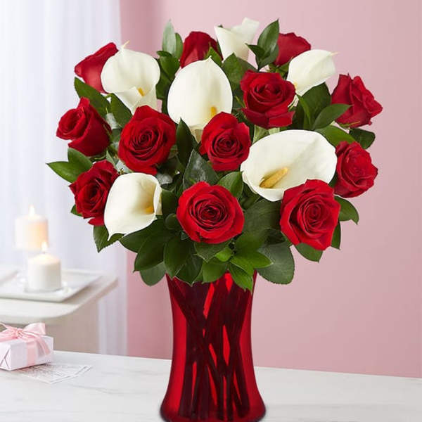 Red roses and white calla lilies in a red glass vase