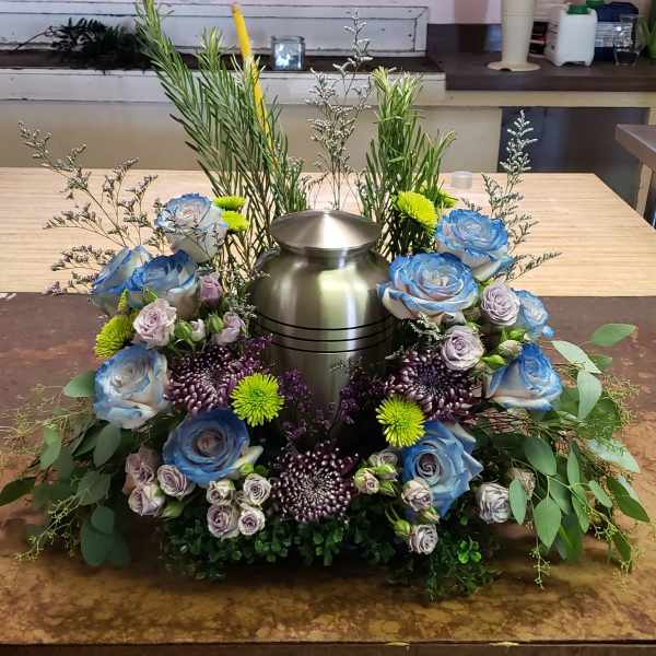 Floral urn arrangement with blue roses and purple chrysanthemums around a metal vase