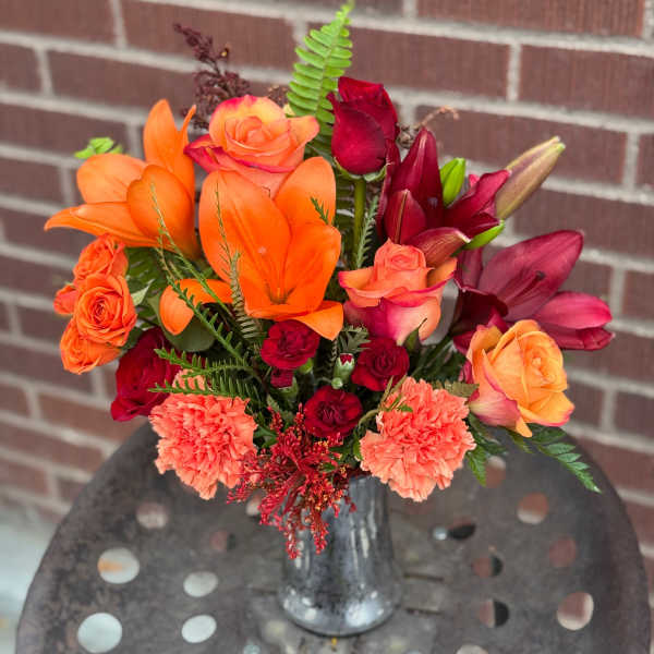 Bouquet of orange and red flowers in a silver vase