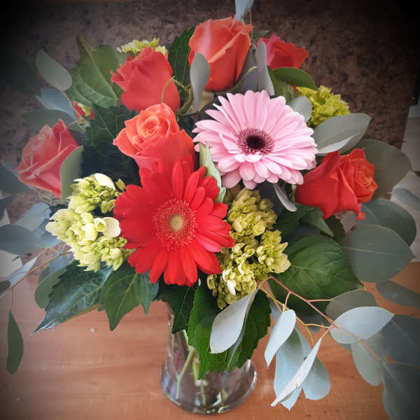 Bouquet of red roses and pink gerbera daisies in a glass vase
