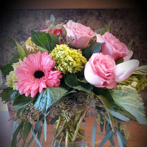 Pink roses and a gerbera daisy in a glass vase