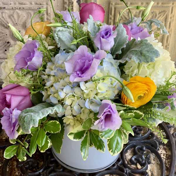 Pastel bouquet of roses, hydrangeas, and lisianthus in a white container