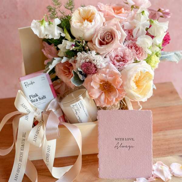 Pastel bouquet in a gift box with chocolates, a candle, and a card