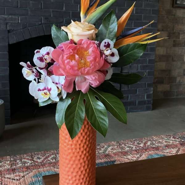 Pink peony and orchids in an orange vase