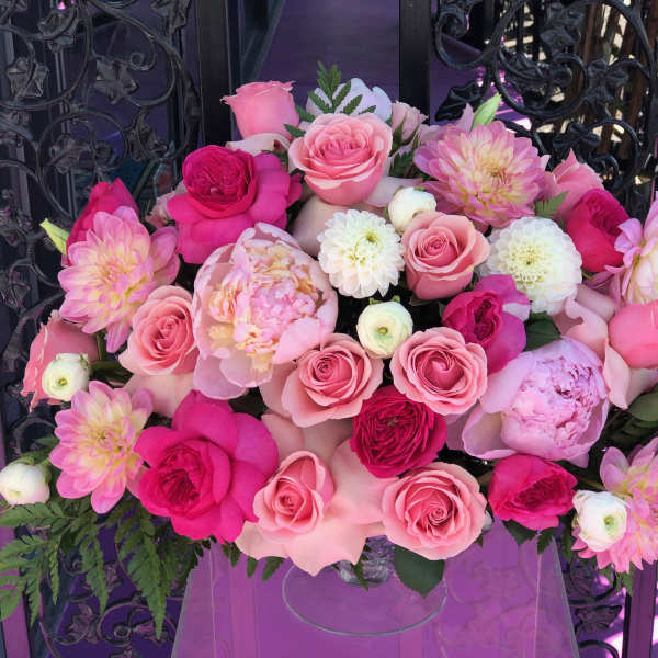Pink and white rose bouquet with dahlia-like blooms in a clear vase