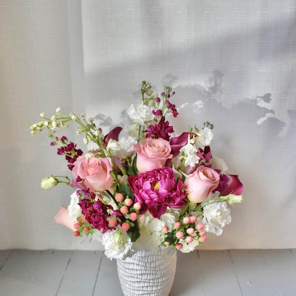Pink and white floral arrangement in a textured white vase