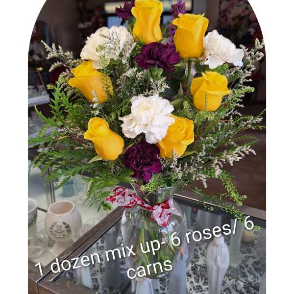 Bouquet of yellow roses and white and purple carnations in a glass vase