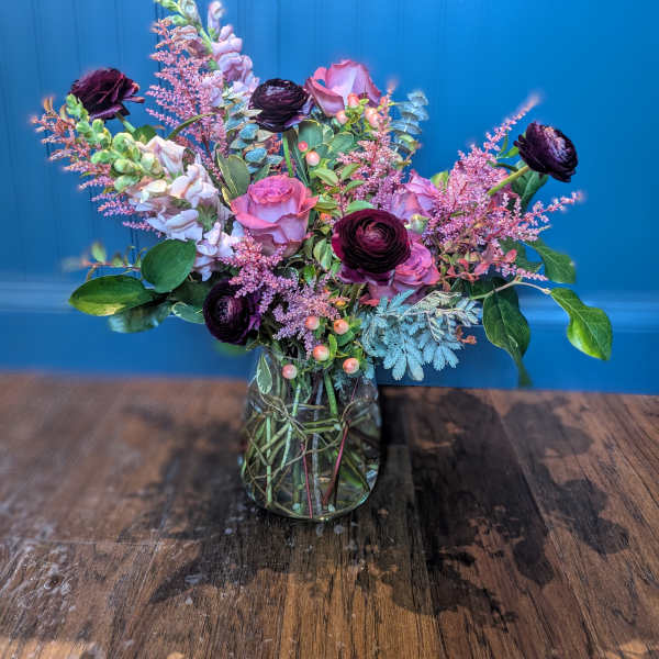 Mixed bouquet of pink and dark purple flowers in a glass vase